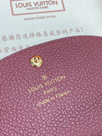 Small Louis Vuitton monogram bag close-up with gold emblem stud on dark plum leather