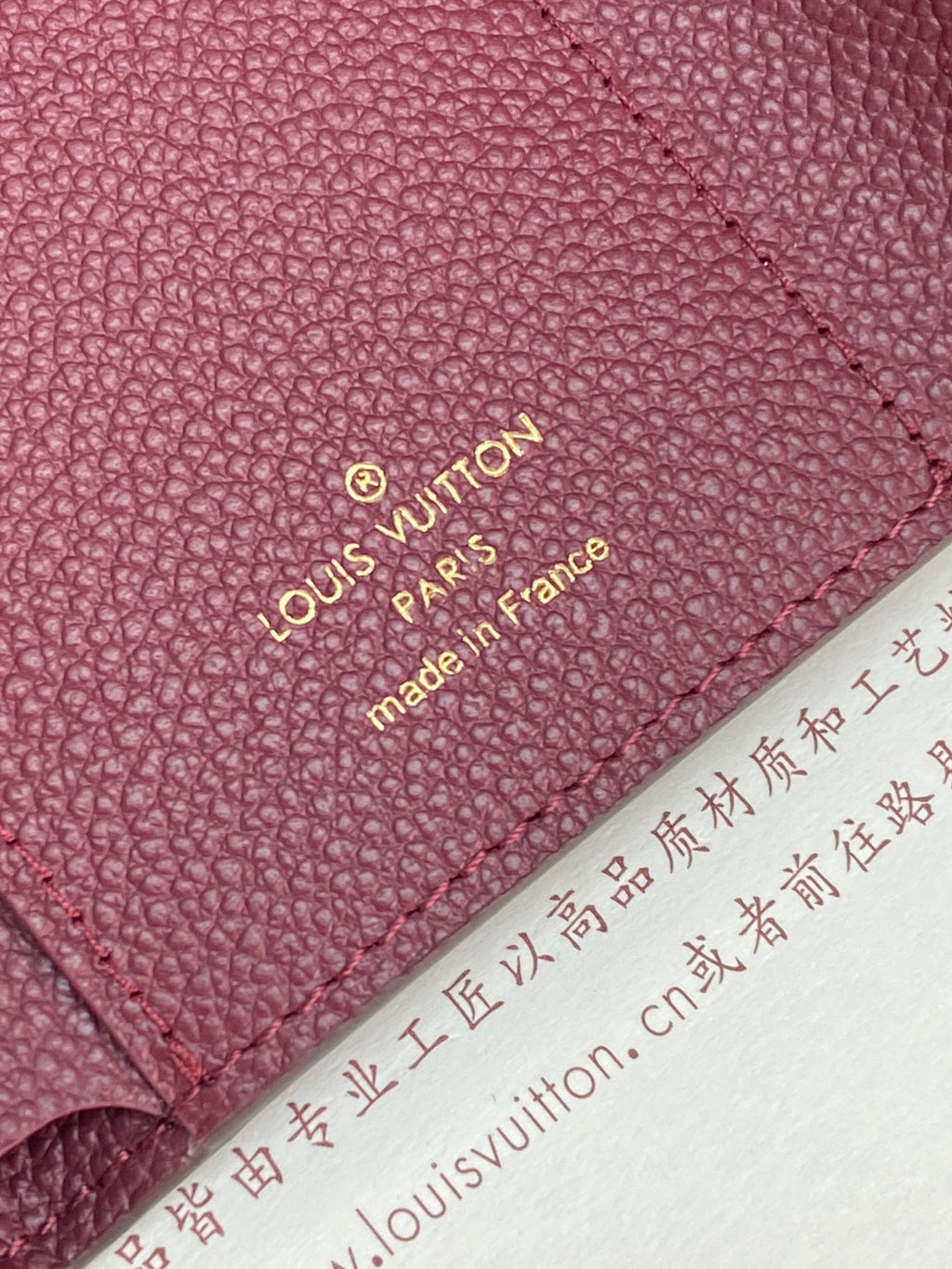 Louis Vuitton leather bag close-up with “Louis Vuitton Paris” stamp on burgundy