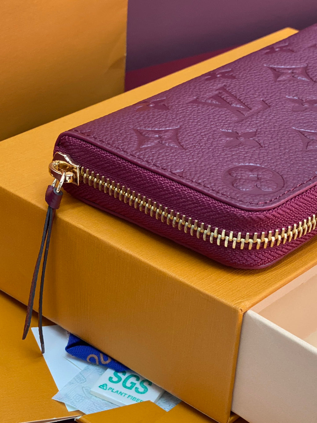 Small purple Louis Vuitton monogram bag with gold zipper and wrist strap attached.