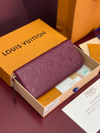 Small purple Louis Vuitton monogram bag with gold zipper and leather pull-tab.