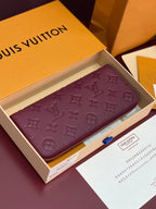 Small purple Louis Vuitton monogram wallet-style bag with gold zip top edge.