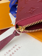Small purple Louis Vuitton monogram bag with gold zipper pull and leather wrist strap.