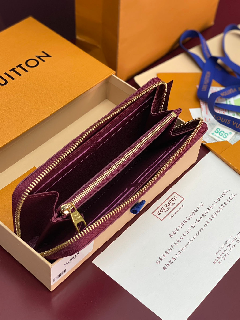 Small purple Louis Vuitton monogram bag opened, showing burgundy interior and gold zippers.