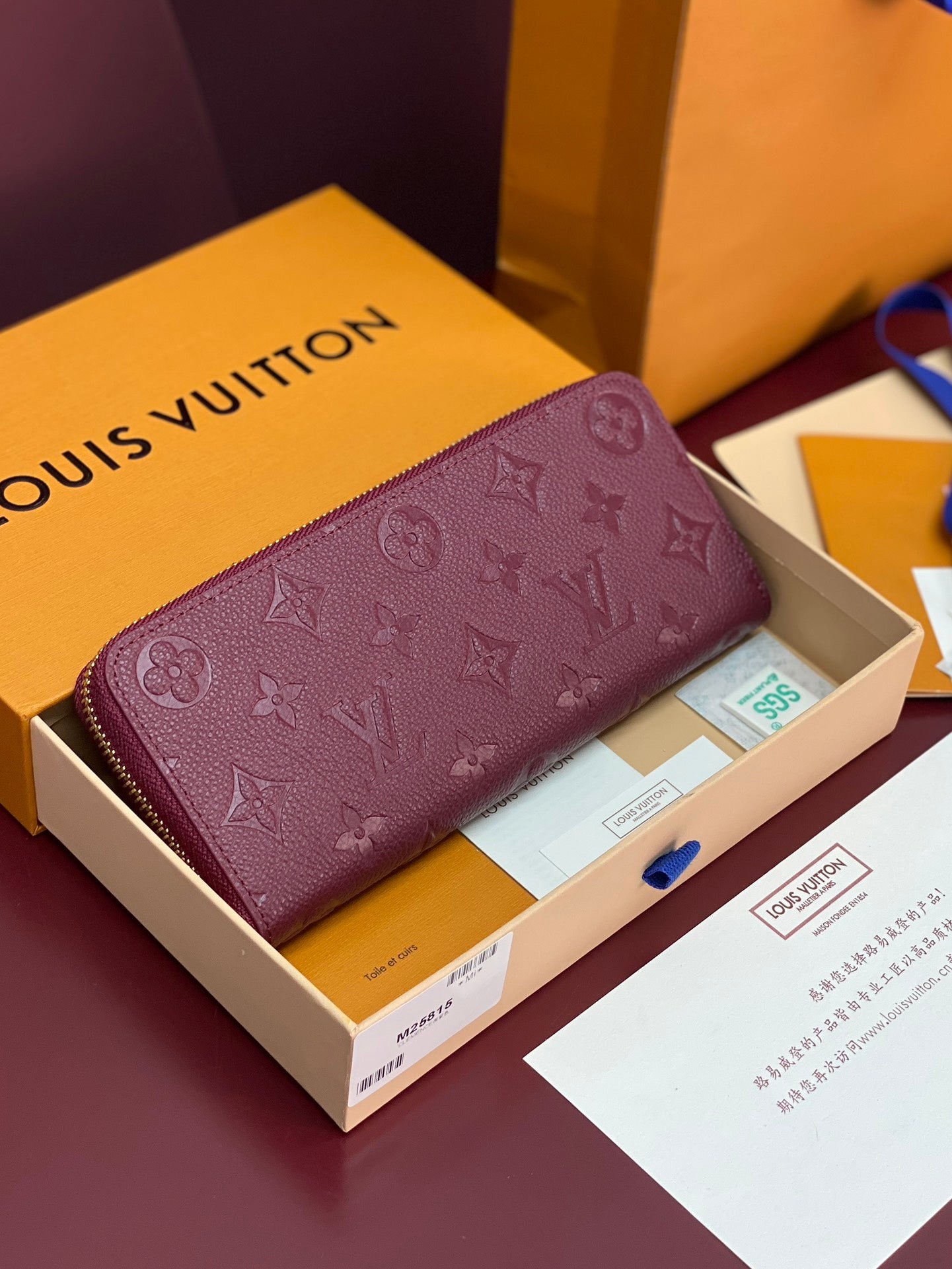 Small bag in purple leather with embossed Louis Vuitton monogram and gold zip closure.