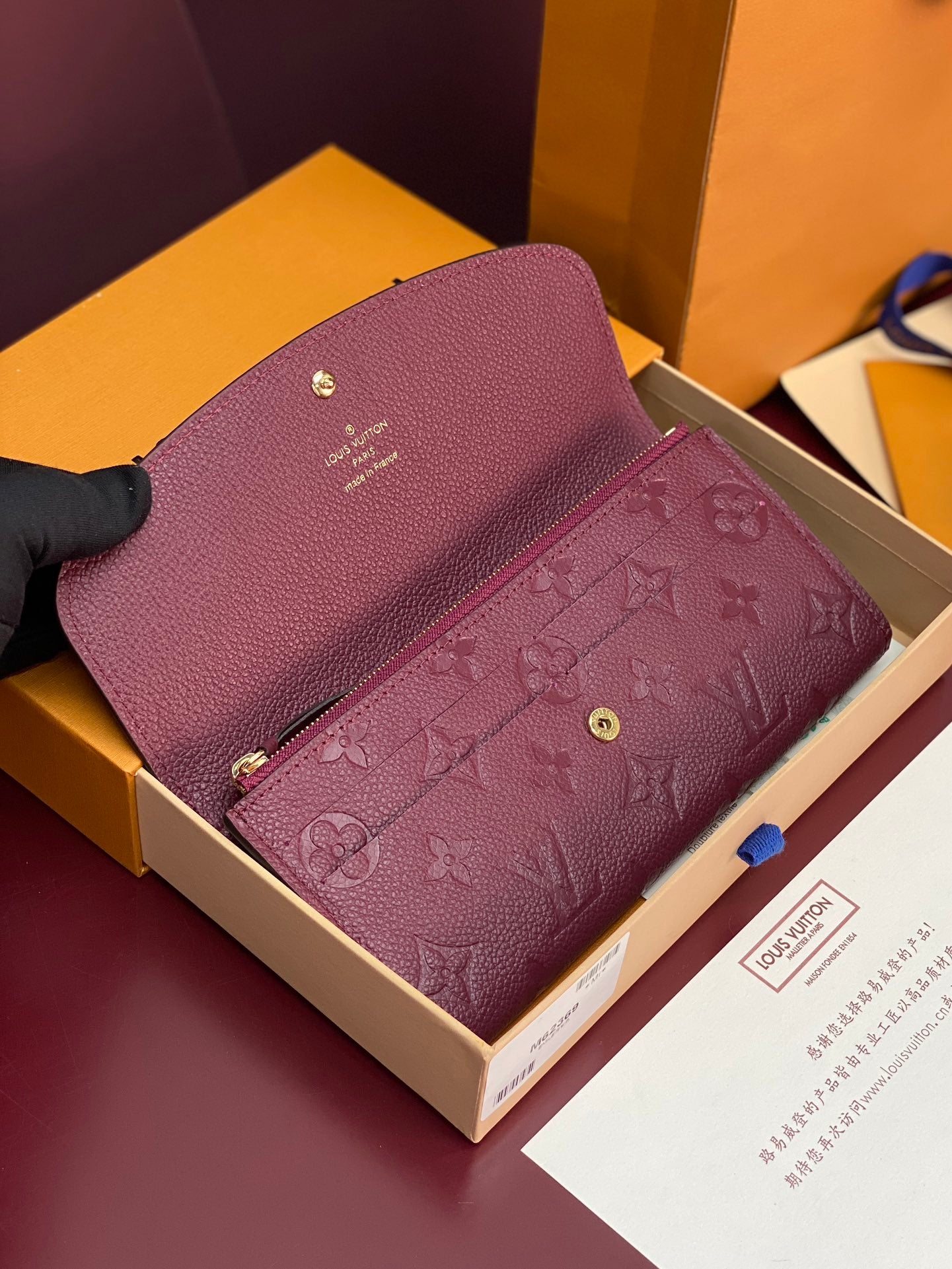 Small bag with burgundy/purple embossed monogram and gold-toned hardware, open front.