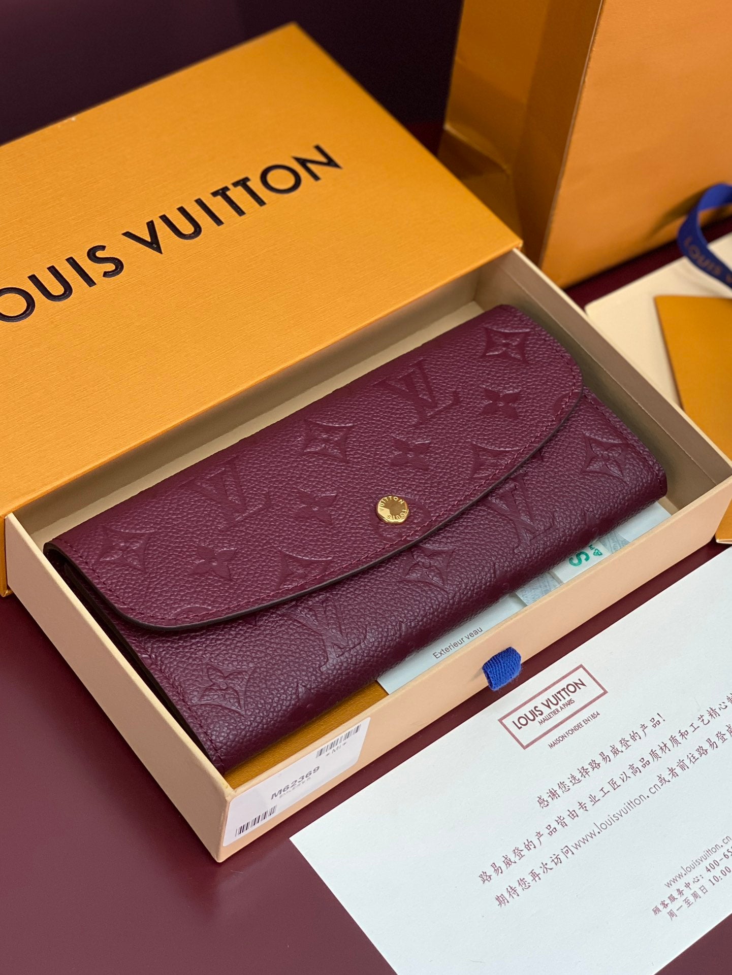 Small bag with flap and burgundy/purple embossed monogram, gold snap button closure.