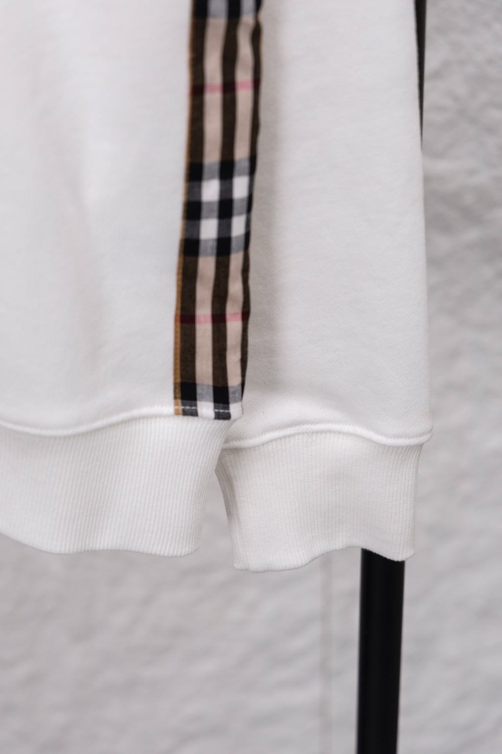White sweatshirt cuff with ribbed hem and vertical checkered sleeve stripe