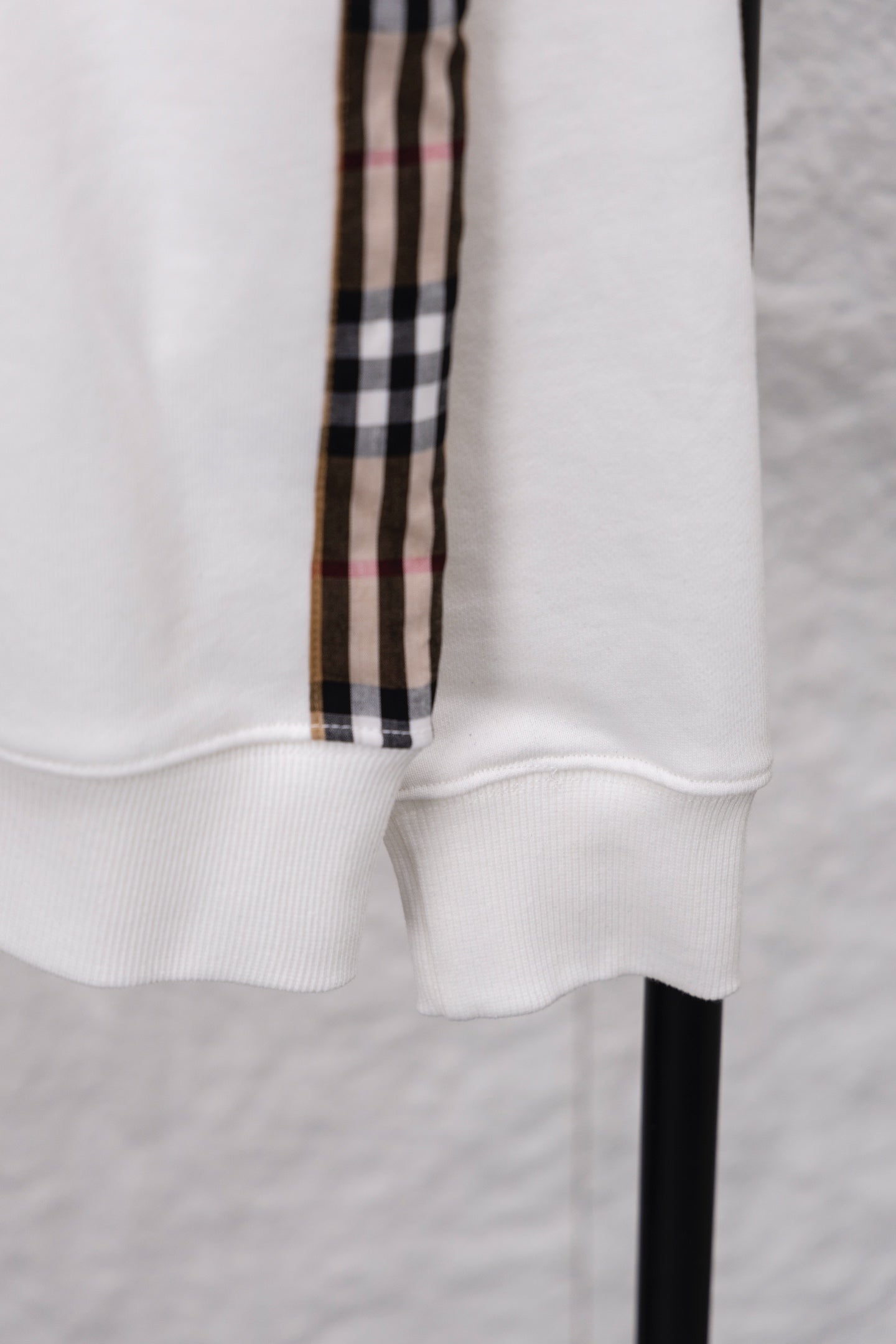 White sweatshirt cuff with ribbed hem and vertical checkered sleeve stripe