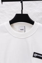 White crewneck sweatshirt with ribbed neckline and black logo patch