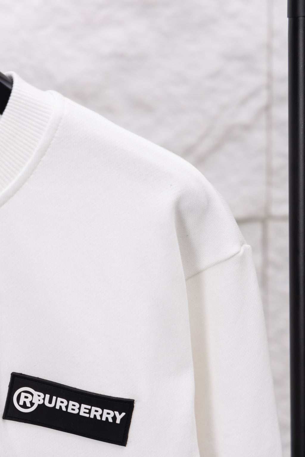 White sweatshirt sleeve with black logo patch on the arm