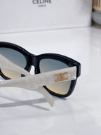Sunglasses close-up with gold logo on temple and dark tinted lens