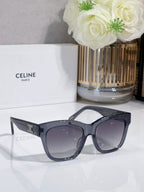 Cat-eye sunglasses with dark lenses and gold logo on temple, shown on case