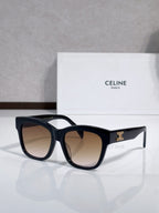 Dark sunglasses with wide cat-eye shape and gold logo on temple