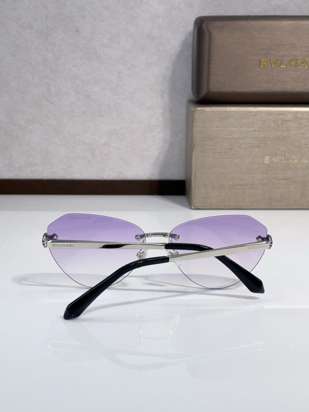 Bvlgari sunglasses side view with purple lenses and black temples, gold metal frame