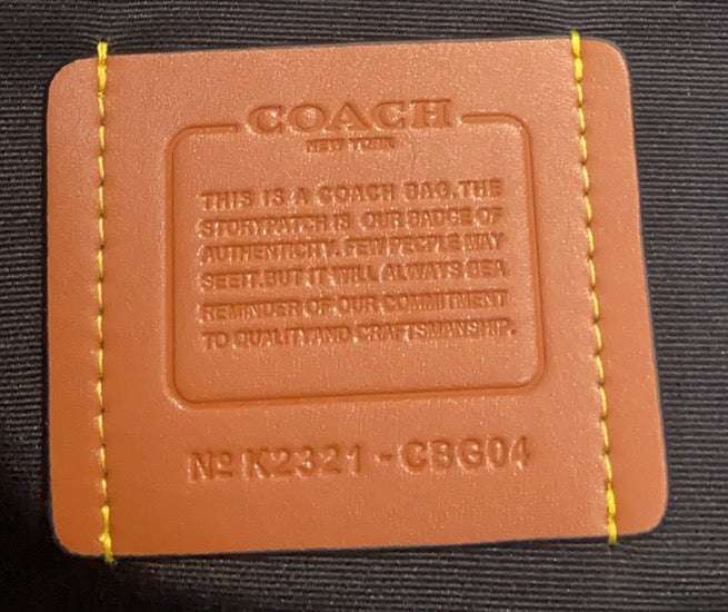 Coah leather-look care label with embossed text on dark fabric