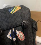 Coah dark monogram backpack close-up of front patch and metal buckle strap