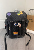 Coah dark monogram backpack with front buckle and colorful collectible patches