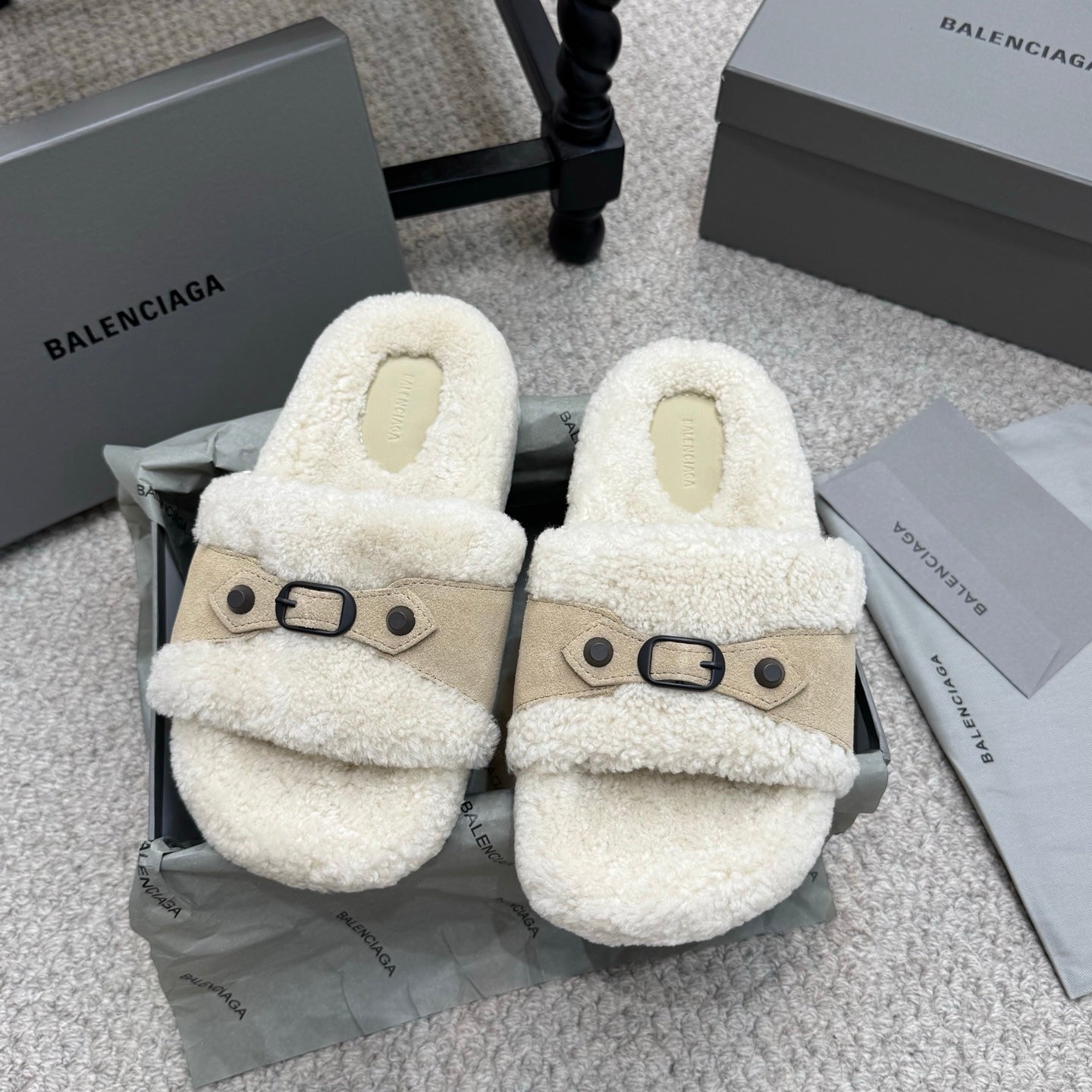 Cream faux-shearling sandals with tan cross strap and black buckle hardware.