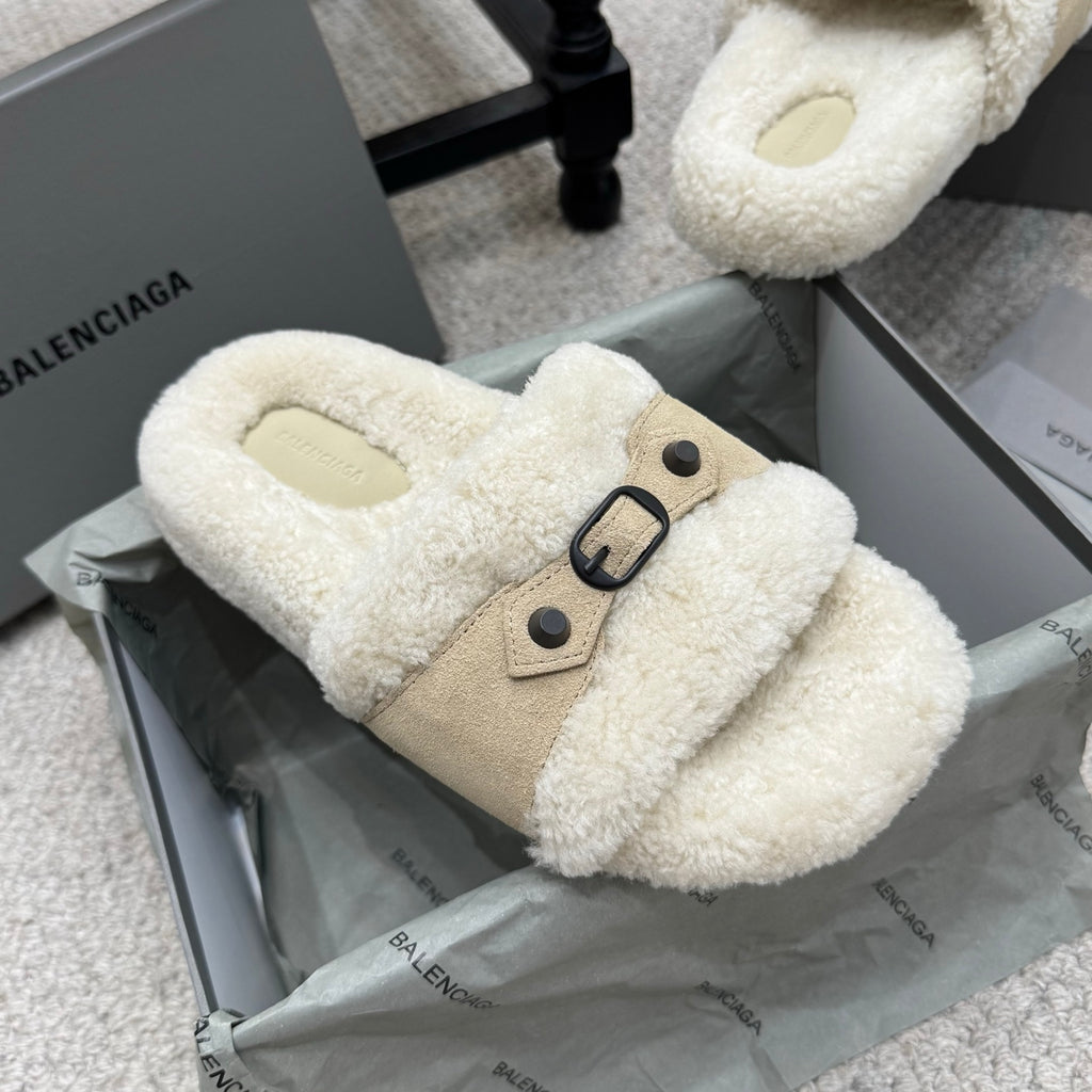 Cream faux-shearling flat sandals with tan buckled strap and oval metal ring.