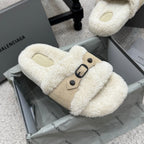 Cream faux-shearling flat sandals with tan buckled strap and oval metal ring.