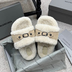 Cream sherpa slide sandals with tan strap, oval buckle, and light footbed.