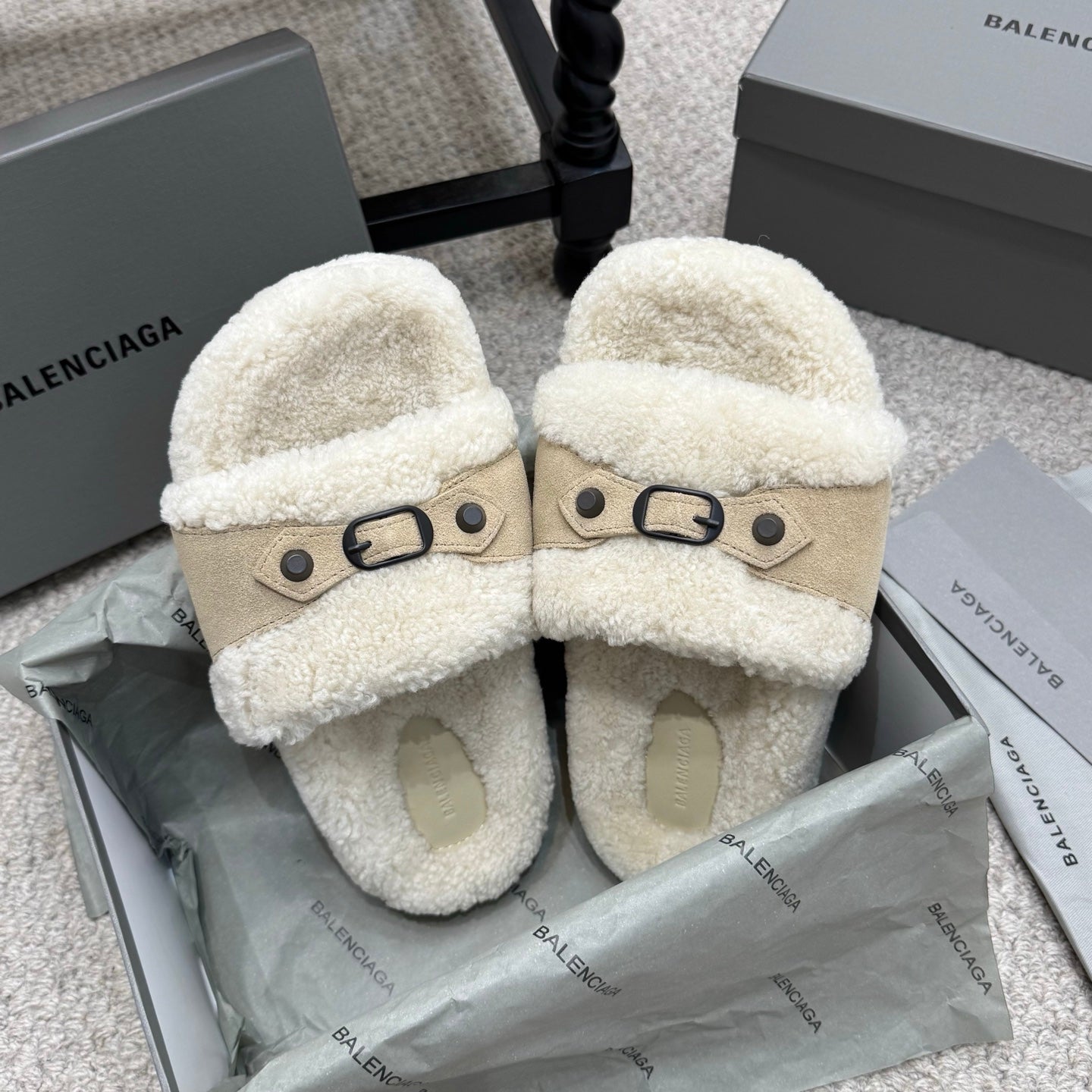 Cream sherpa slide sandals with tan strap, oval buckle, and light footbed.