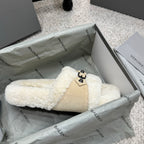 Cream faux-shearling mule sandals with tan strap panel and black buckle detail.