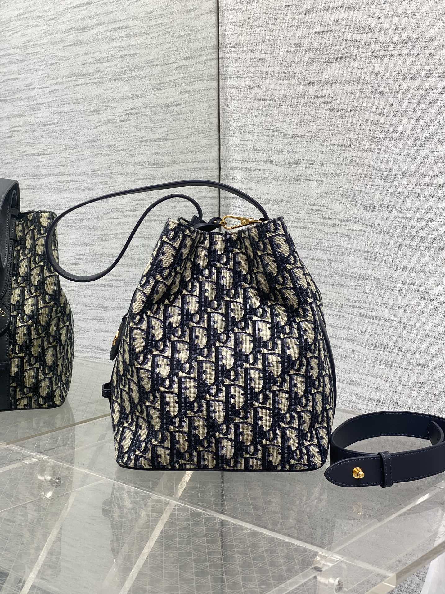 Dior Oblique canvas drawstring bucket bag with navy shoulder strap and gold clasp