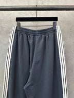 Balenciaga track pants with elastic waist and dark blue fabric, white side stripe bands