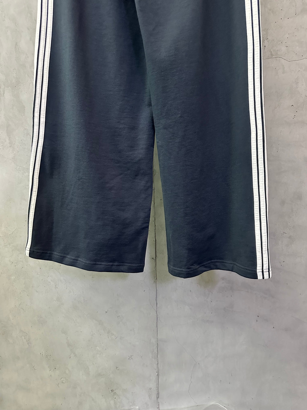 Balenciaga dark blue track pants showing wide leg silhouette and side stripe detail