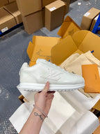 White leather low-top sneakers with lace-up top, embossed side logo, and white sole