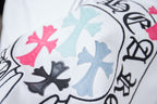 Close-up of circular crest graphic with pink and light-blue cross shapes on white tee