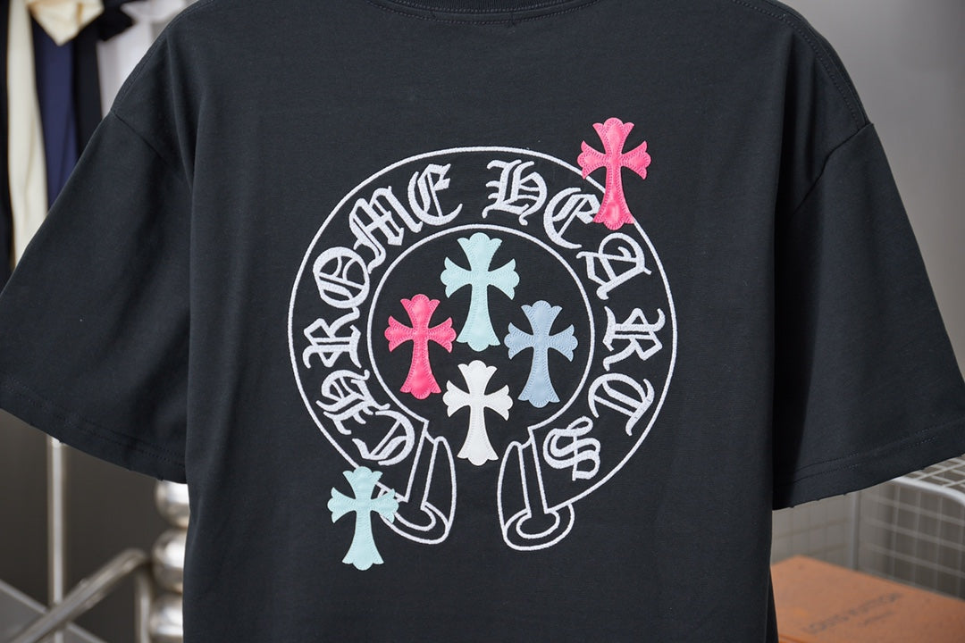 Black T-shirt back with large circular logo featuring pink and teal cross details