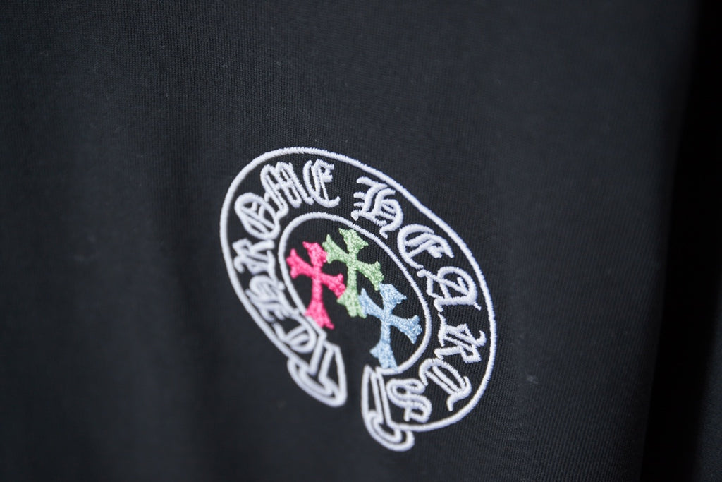 Black T-shirt with circular logo in white outline with pink and light blue crosses