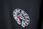 Black T-shirt with circular logo in white outline with pink and light blue crosses