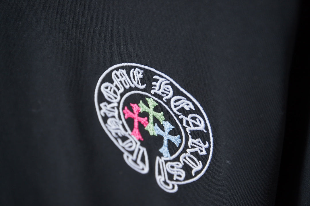 Black T-shirt with circular logo in white outline with pink and light blue crosses
