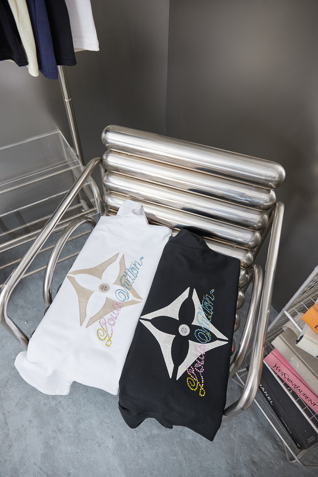 Folded Louis Vuitton T-shirt set on metal stand: black and white tees with logos