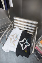 Folded Louis Vuitton T-shirt set on metal stand: black and white tees with logos