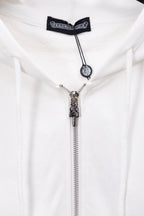 White zip-up hoodie close-up of metallic zipper pull and cord charm