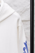 White hoodie sleeve with blue ornamental print near hem