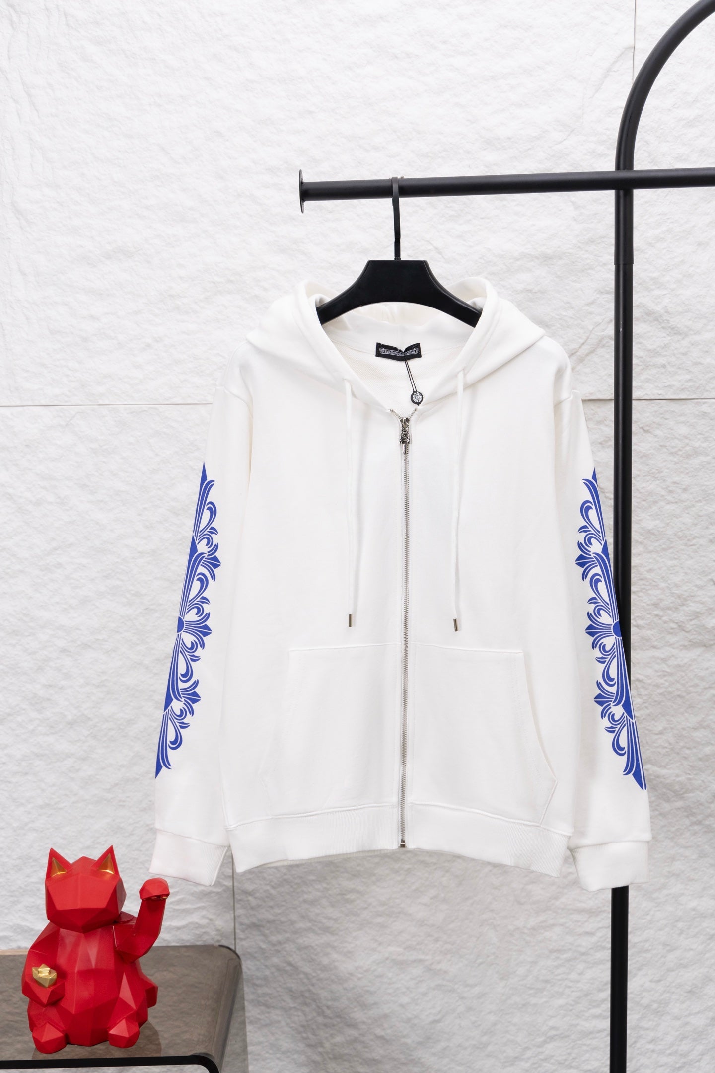 White zip-up hoodie with blue sleeve ornament print and front kangaroo pocket