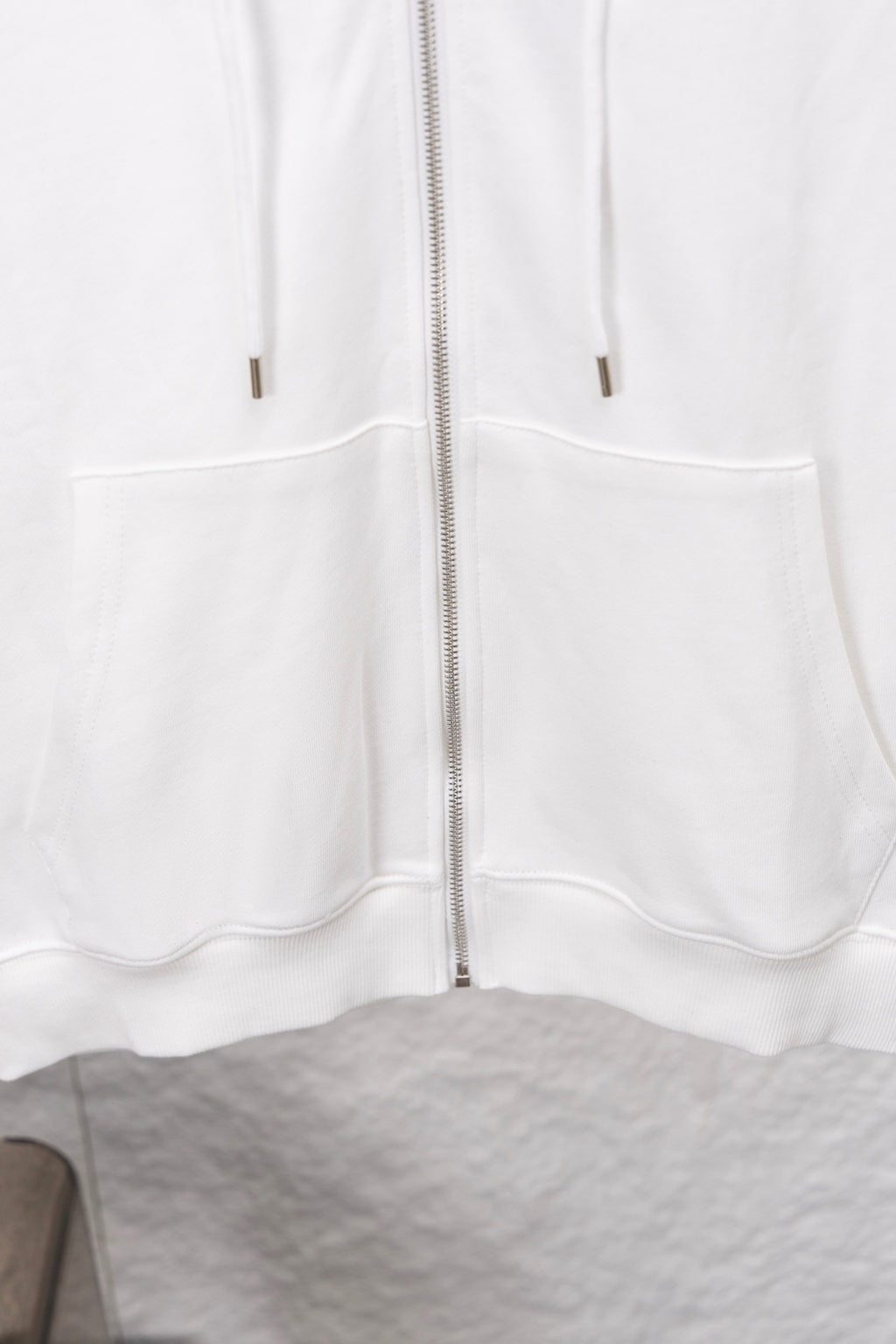 White zip-up hoodie front with kangaroo pockets and zipper center seam