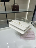 Stacked white and lavender quilted flap shoulder bags with gold clasps