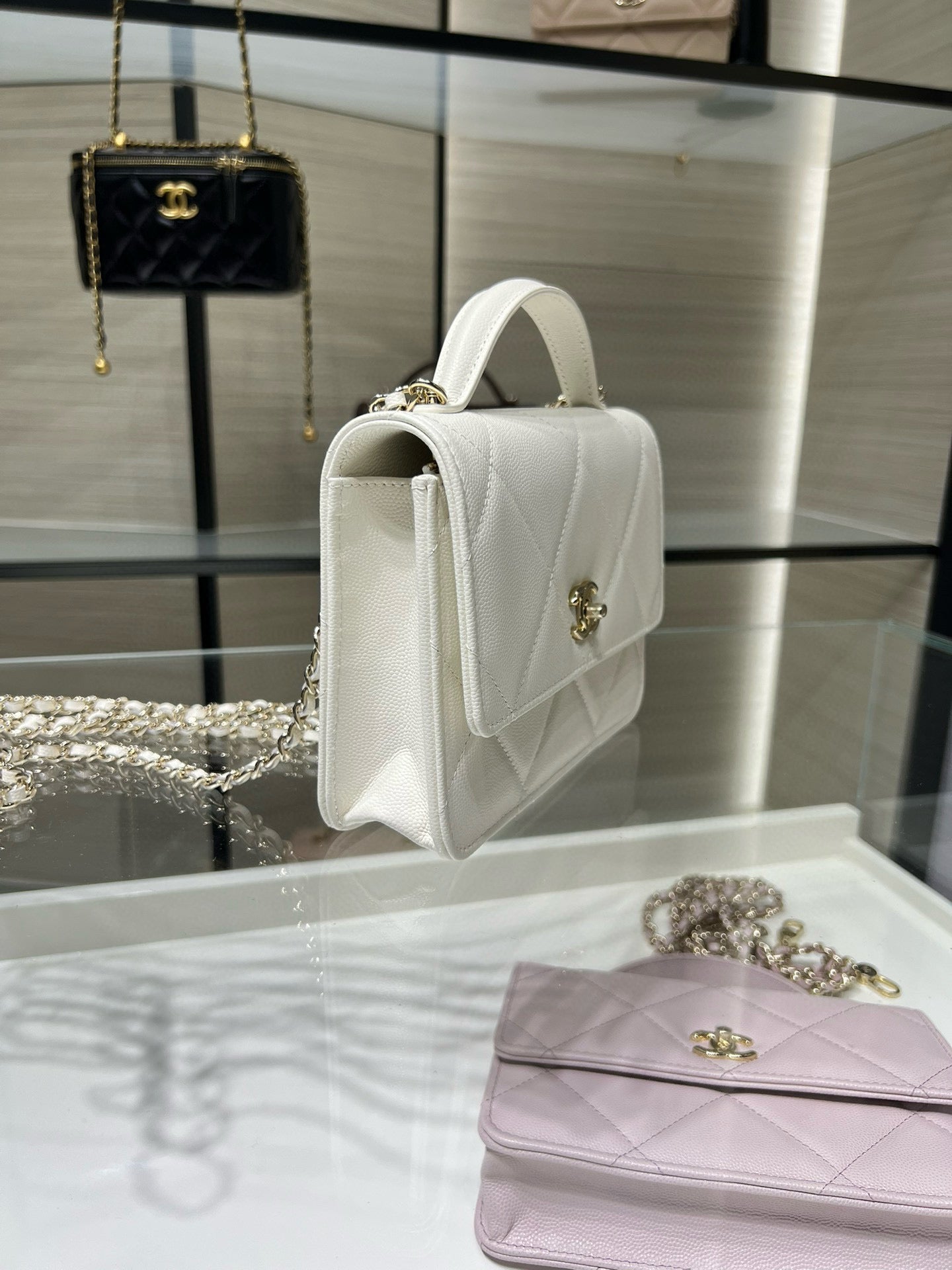 White quilted shoulder bag side view with top handle and gold CC clasp