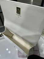 White pebbled leather bag with gold Chanel label plate and chain strap