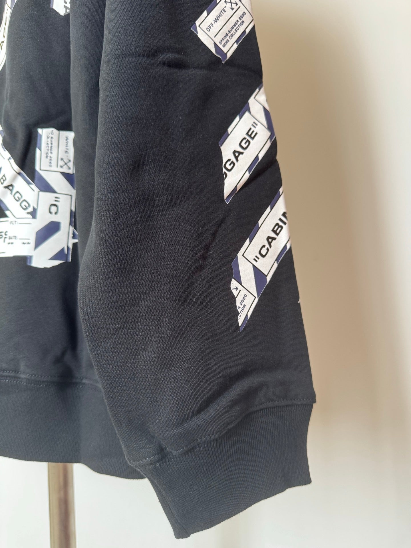 Black hoodie lower sleeve with Cabin Baggage graphic print and ribbed cuff
