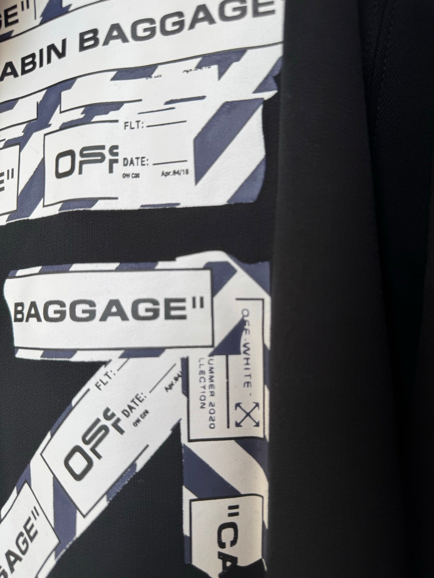 Black hoodie sleeve with Cabin Baggage label graphics and printed text