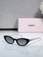 Cat-eye sunglasses with dark lenses and black frames; logo on temple.