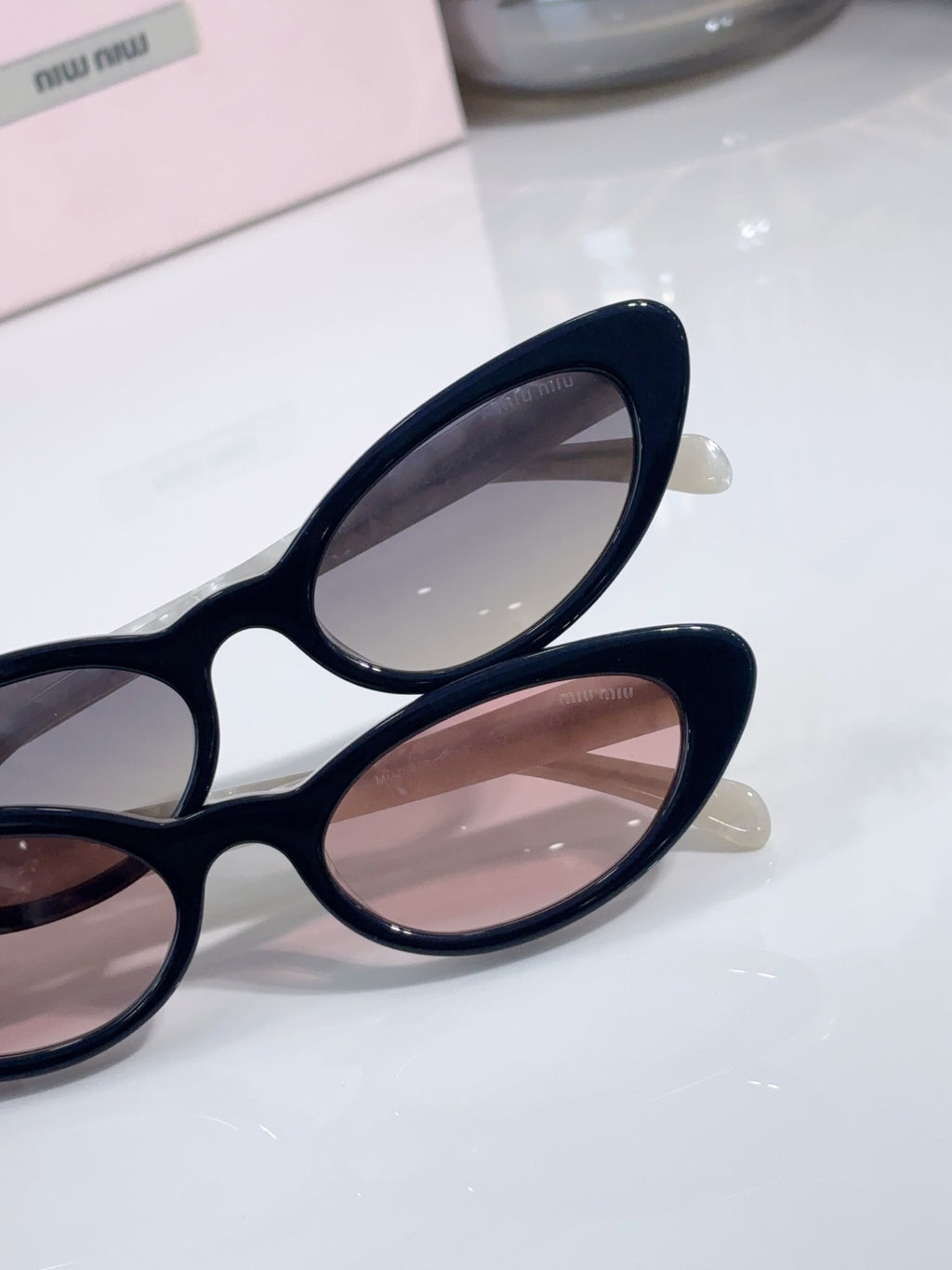Close-up of cat-eye sunglasses with dark frames and pink-tinted lenses.
