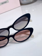 Close-up of cat-eye sunglasses with dark frames and pink-tinted lenses.